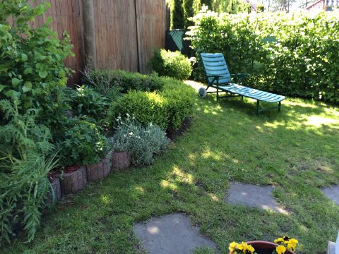 Eingezäunter Garten mit Sonnenliege und Beeten